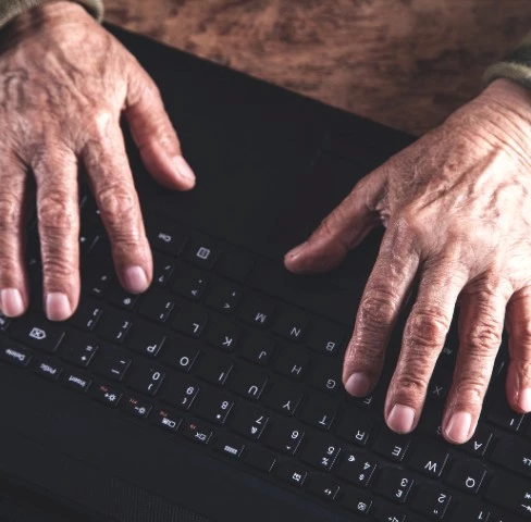 Billede af en ældre kvinde, der sidder med en mobiltelefon i hånden